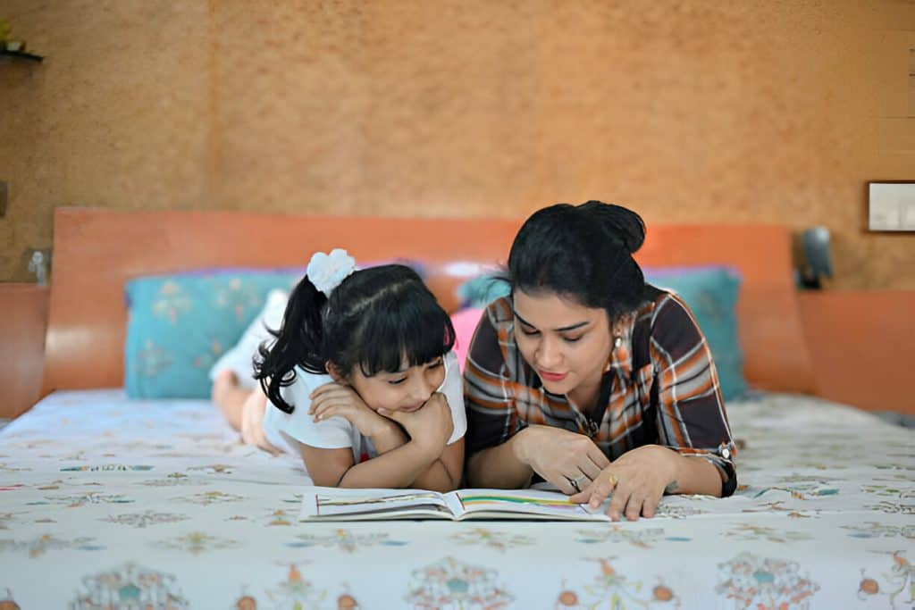 cute mom and girl reading in bed